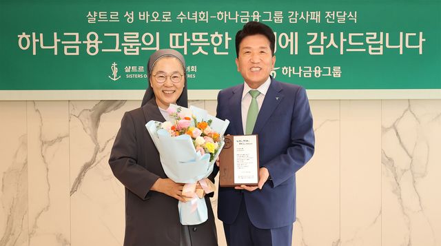 감사패 전달식에 참석한 함영주 하나금융그룹 회장(사진 오른쪽)이 민혜숙(세례명: 효임 골룸바) 샬트르 성 바오로 수녀회 서울 관구장(사진 왼쪽)과 함께 감사패와 꽃다발을 들고 기념촬영을 하고 있다. / 사진=하나금융그룹