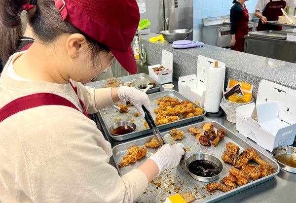 경기도 오산시의 교육 및 R&D센터 정구관(교촌 아카데미) 내 브랜드 체험관에서 열린 '교촌1991 소비자 캠프'에서 참여자들이 양념을 일일이 치킨에 붓으로 바르고 있다. 양념 붓질은 교촌치킨의 독특한 조리법으로 브랜드 시그니처로 여겨진다. 교촌치킨은 최근 일부 메뉴의 조리 방식을 붓질에서 텀블링(치킨을 양념에 버무리는 것)으로 변경한다고 발표했다가 여론의 뭇매를 맞고 붓질 도포로 되돌리겠다고 공식화했다. / 사진=교촌치킨