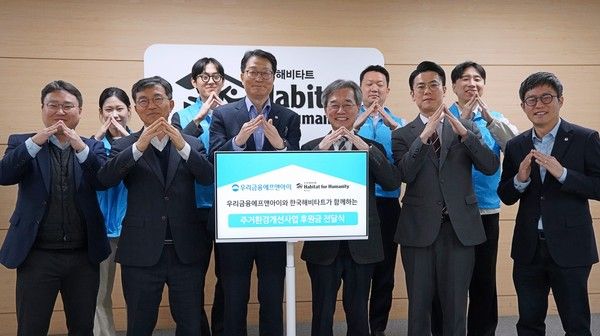 (왼쪽에서 다섯번째부터)&nbsp;우리금융에프엔아이 김건호 대표이사와 이광회 사무총장이 지난&nbsp;24일 한국해비타트 본사에서 열린 후원금 전달식에서 양사 임직원과 함께 기념 촬영을 하고 있다. / 사진=우리금융에프앤아이.&nbsp;