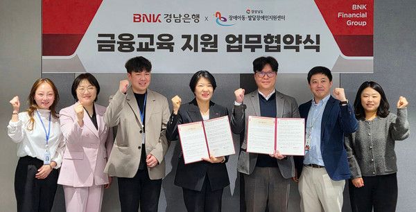BNK경남은행 김경옥 상무(사진 왼쪽 네번째)와 경상남도발달장애인지원센터 이동욱 센터장이 '금융교육 지원 업무협약'을 체결하고 있다. / 사진=BNK경남은행.
