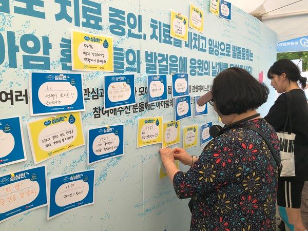 환아 그림 공모전 작품들이 전시된 행사 부스에서 참가자들이 환아들에게 보내는 응원 메시지를 벽에 부착하고 있다. /사진=김현정 기자