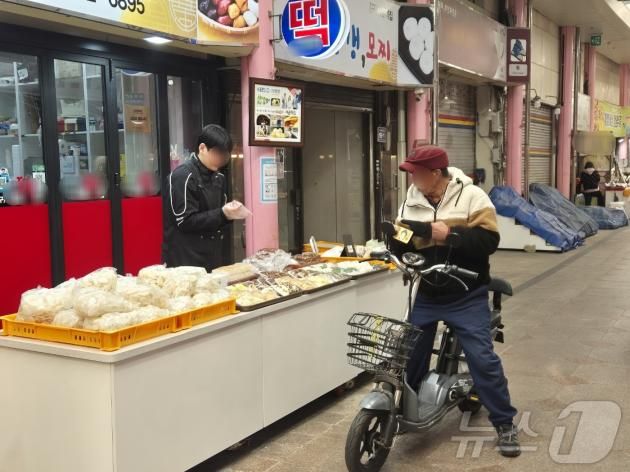 장을 보러온 송 모씨(85)가 26일 오전 인천 중구 신포국제시장을 방문해 떡을 사고 있는 모습.2025.1.26/뉴스1 ⓒ News1 이시명기자