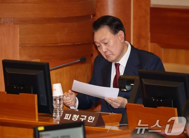 윤석열 대통령이 23일 오후 서울 종로구 헌법재판소 대심판정에서 열린 탄핵심판 4차 변론기일에 출석해 메모지를 살펴보고 있다. 2025.1.23/뉴스1 ⓒ News1 사진공동취재단