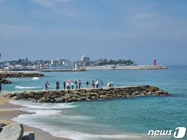 드라마 '도깨비' 촬영지인 강원 강릉 주문진읍 '도깨비 방사제'에서 기념사진 촬영하는 관광객들. 뒤로 보이는 빨간등대는 드라마 '더글로리' 마지막회가 촬영된 '소돌 방파제다'. ⓒ News1 윤왕근 기자