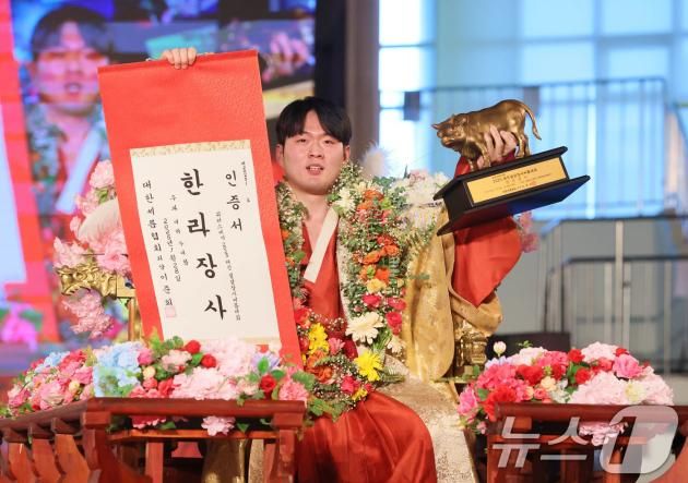 28일 충청남도 태안군 태안종합실내체육관에서 열린 ‘위더스제약 2025 태안설날장사씨름대회’에서 한라장사(105kg이하)에 등극한 박민교(용인특례시청)가 장사꽃가마를 타고 장사인증서와 황소트로피를 들어 보이고 있다. (대한씨름협회 제공)2025.1.28/뉴스1