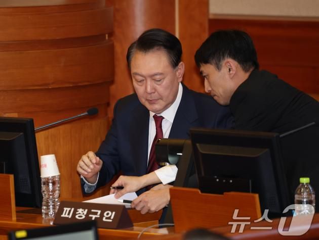 윤석열 대통령이 23일 오후 서울 종로구 헌법재판소 대심판정에서 열린 탄핵심판 4차 변론기일에 출석해 메모지를 건네받고 있다. 2025.1.23/뉴스1 ⓒ News1 사진공동취재단