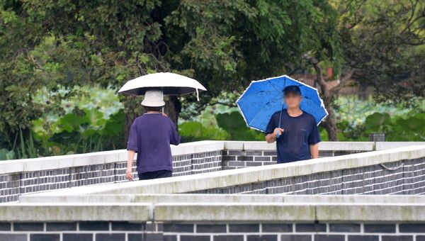 ▲ 전북 전주시 전주덕진공원을 찾은 시민들이 우산으로 비를 피하며 길을 지나고 있다. 사진=뉴시스