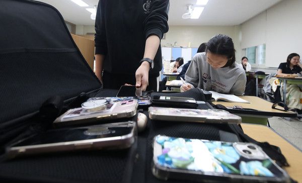 ▲ 지난 10월 15일 대구 수성구 정화여고 3학년 교실에서 학생들이 전국연합학력평가 시험을 치르기 위해 휴대전화를 수거용 가방에 제출하고 있다. 사진=뉴시스