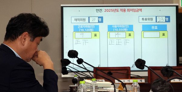 ▲ 이인재 최저임금위원장이 12일 새벽 세종시 정부세종청사에서 2025년도 적용 최저임금이 결정된 뒤 자리에 앉아 있다. 뒤쪽으로 내년도 최저임금은 10030원 결정된 표결결과가 보이고 있다. 사진=뉴시스