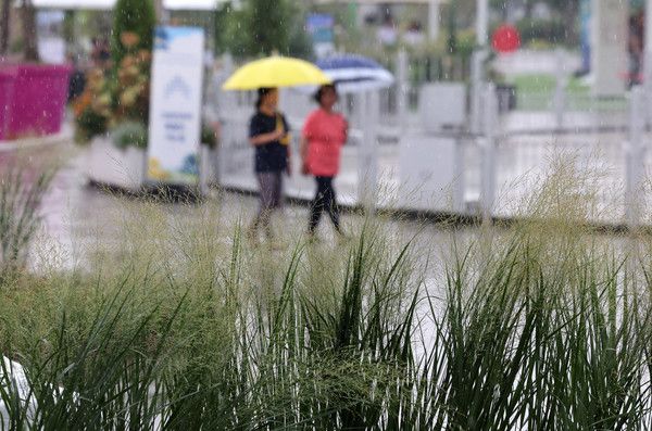 ▲ 갑작스레 소나기가 내린 지난달 26일 오후 서울 광진구 뚝섬한강공원에서 열린 2024 대한민국정원산업박람회를 찾은 시민들이 우산을 쓰고 이동하고 있다. 사진=뉴시스