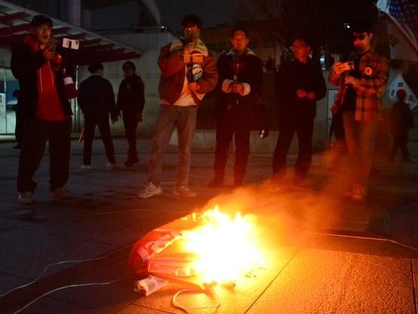 ▲ 11일 충북대학교에서 보수 성향 유튜버와 시민들이 탄핵 찬성 집회 측이 현장에 놓고간 현수막을 불태우고 있다. 사진=뉴시스