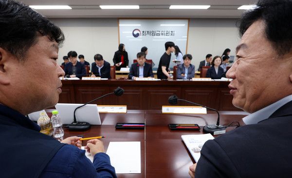 ▲ 22일 세종시 정부세종청사에서 열린 최저임금위원회 제1차 전원회의에서 류기정 사용자 위원(오른쪽)과 류기섭 근로자 위원이 대화하며 미소 짓고 있다. 사진=뉴시스