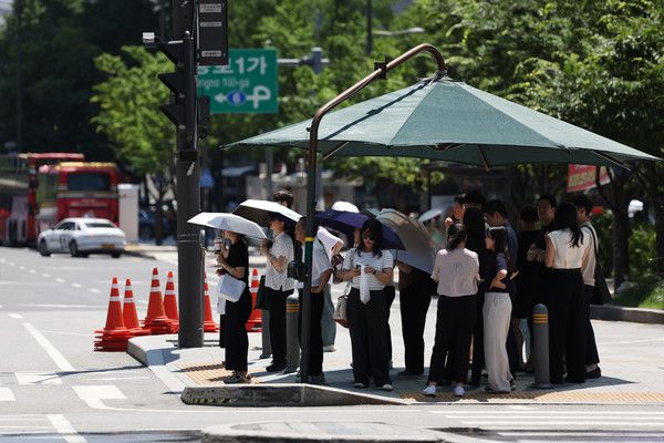 ▲ 서울 종로구 인근에서 시민들이 보행신호를 기다리며 그늘막아래에서 햇볕을 피하고 있다. 사진=뉴시스