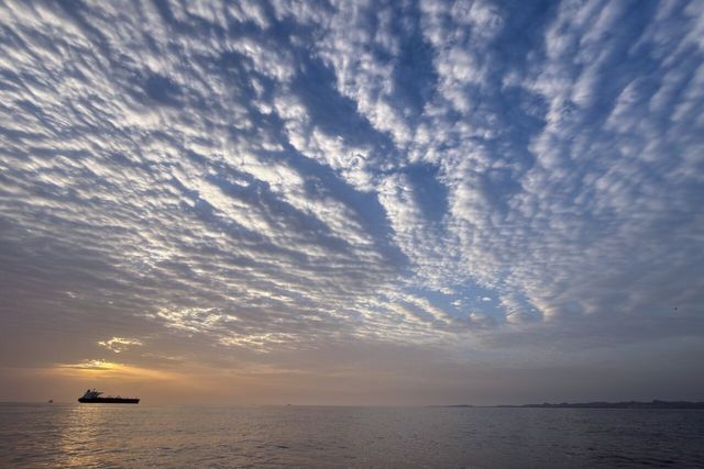▲ 18일(현지시간) 이란 케심섬 연안 호르무즈 해협에 정박한 유조선 뒤에서 해가 뜨고 있다. 사진=뉴시스