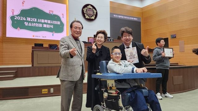 ▲ 문성호 서울시의원(오른쪽)이 지난 2024년 제2대 서울특별시의회 청소년의회 폐회식에서 조온유 청소년의원(중앙 휠체어)과 함께 기념사진을 촬영하고 있다. 사진=서울시의회