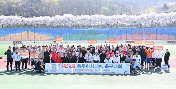 '제39회 동두천시장배 축구대회'에서 참가 선수단과 박형덕 동두천시장 등 주요 내빈들이 벚꽃이 만개한 운동장을 배경으로 파이팅을 외치며 기념 촬영을 하고 있다. /사진=동두천시