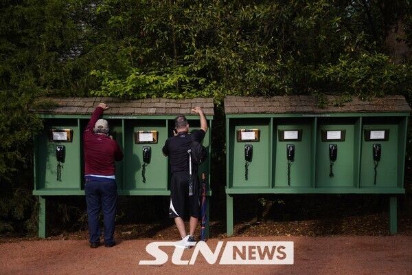 마스터스 골프 대회 연습 라운드가 열린 지난 2022년 4월 5일(현지시간) 미국 조지아주 오거스타 내셔널 골프클럽에서 휴대전화 반입이 금지된 가운데, 관람객들이 7번 홀 인근에 구비된 전화부스를 사용하고 있다. /사진=뉴시스(AP)