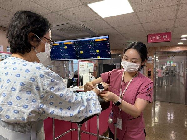 간호사가 환자에게 스마트 병상 모니터링 시스템 '씽크'와 연동되는 웨어러블 기기를 착용시키고 있다. 대웅제약 제공 [뉴스락]