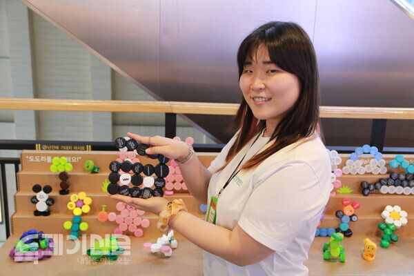 제20회 서울국제환경영화제 김수연 프로그램팀 매니저가 폐플라스틱 병뚜껑으로 직접 만든 영화 슬레이트를 들고 서있다.&nbsp;ⓒ투데이신문