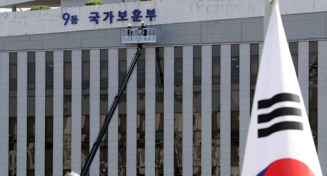 국가보훈부 승격을 앞뒀던 지난해 5월 31일 세종시 어진동 정부세종청사 국가보훈처 외벽에 대형 현판 교체작업이 진행되고 있다. [사진제공=뉴시스]<br>