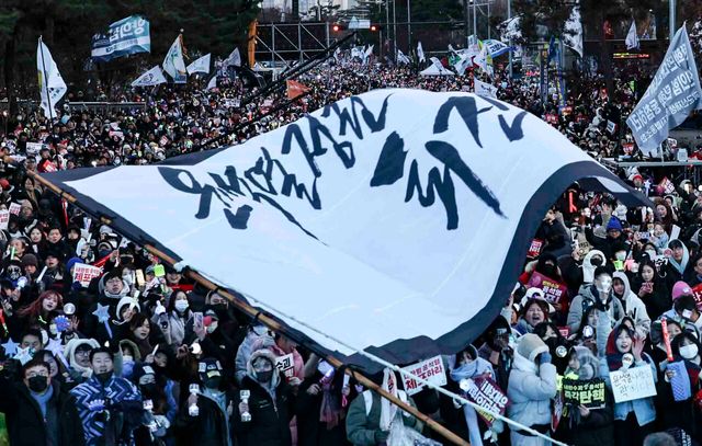 윤석열 대통령에 대한 탄핵 소추안 재표결이 통과된 지난 14일 서울 여의도 국회의사당 앞에서 시민들이 탄핵소추안 국회 통과에 기뻐하고 있다. [사진출처=뉴시스]