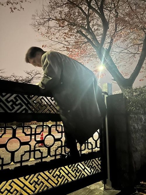 우원식 국회의장이 지난 3일 밤 윤석열 대통령의 비상계엄 선포에 국회 출입이 통제되자 담장을 넘어가고 있다. [사진 제공=국회의장실]<br>