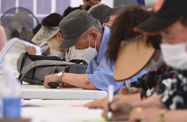 2022년 6월 21일 경기도 수원시 팔달구 화성행궁광장에서 진행된 ‘노인일자리 채용한마당’을 방문한 어르신들이 구직신청서를 쓰고 있다. [사진제공=뉴시스]<br>