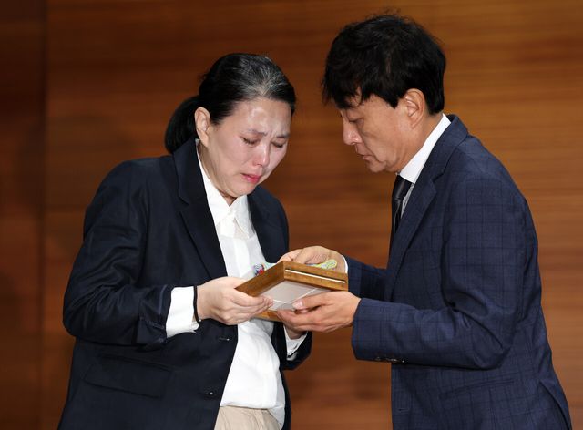 고 오요안나씨 어머니 장연미씨가 15일 오전 10시 서울 마포구 MBC에서 열린 고 오요안나 1주기 관련 대국민 기자회견에서 MBC 안형준 사장에게 명예사원증을 전달 받고 있다. [사진제공=뉴시스]