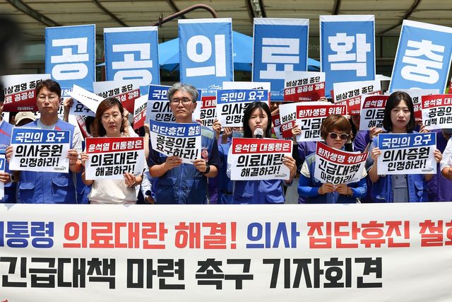 전국민주노동조합총연맹 공공운수노조 의료연대본부 조합원들이 지난 2024년 6월 14일 오후 서울 종로구 서울대학교 병원 앞에서 열린 윤석열 정부 의료대란 해결 촉구와 의사 집단 휴진을 규탄하는 기자회견에서 손피켓을 들고 서 있다.