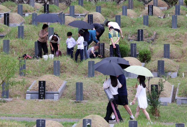 지난 28일 부산 금정구 영락공원을 찾은 시민들이 비가 내리는 궂은 날씨 속에서 성묘와 벌초를 하고 있다. [사진=뉴시스]