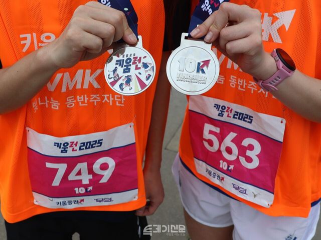 마라톤에서 함께 달린 최경록(44) 참가자와 남유원(36) 참가자가 10km 완주 메달을 들어 보여주고 있다. ⓒ투데이신문