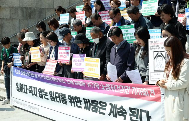 28일 서울 종로구 광화문 세종문화회관 계단에서 진행된 4.28 ‘산재노동자의날 국가기념일 제정 원년. 산재 피해자유가족 기자회견’에서 관계자들이 묵념하고 있다. [사진제공=뉴시스]<br>