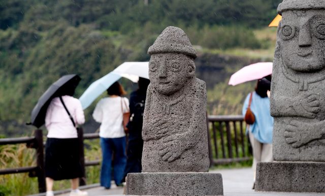 올해 첫 장맛비가 시작된 12일 오전 제주 서귀포시 대정읍 송악산 둘레길에서 우산을 쓴 관광객들이 발걸음을 옮기고 있다. [사진제공=뉴시스]<br>