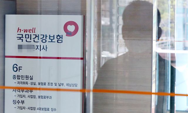 2023년 4월 서울 소재 국민건강보험 지사의 입구에 한 남성의 실루엣이 비치고 있다. [사진제공=뉴시스]