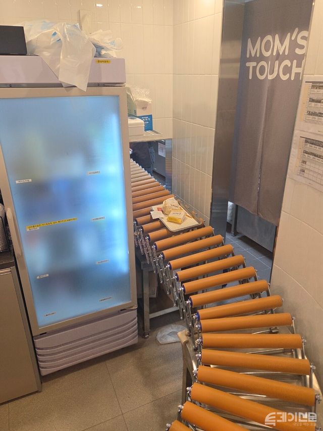 맘스터치 광화문점 주방과 픽업대 사이를 잇는 컨베이어 벨트에서 조리된 음식이 운송되고 있다. ⓒ투데이신문