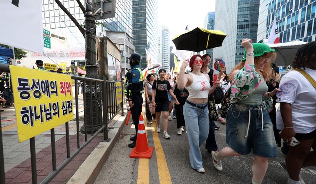 지난 14일 제26회 서울퀴어문화축제 참가자들이 퀴어퍼레이드를 하는 옆으로 기독교 단체 회원들이 반대 집회 현수막이 걸려 있다. [사진제공=뉴시스]