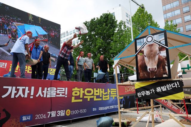 전국한우협회 소속 한우농민들이 지난 2024년 7월 서울 여의도 국회 앞에서 열린 ‘한우산업 안정화 촉구 한우 반납 투쟁 집회에서 사료포대를 던져 소 축사 모형을 부수는 퍼포먼스를 하고 있다. [사진제공=뉴시스]