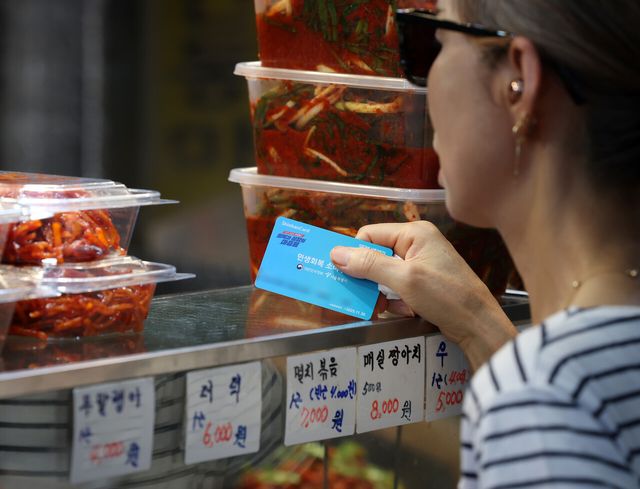 서울 시내의 한 전통시장에서 한 시민이 민생회복 소비쿠폰을 이용해 반찬을 구매하고 있다. [사진=뉴시스]