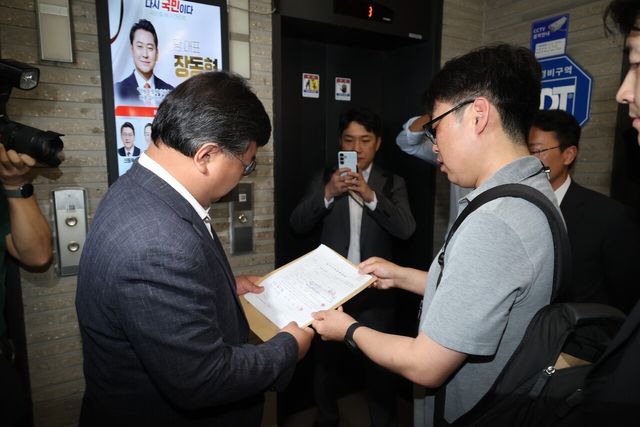 김건희 여사의 의혹들을 수사하는 민중기 특별검사팀이 '통일교 집단 입당' 의혹과 관련해 18일 서울 여의도 국민의힘 중앙당사 앞에서 변호사에게 압수수색 영장을 제시하고 있다. [사진제공=뉴시스]