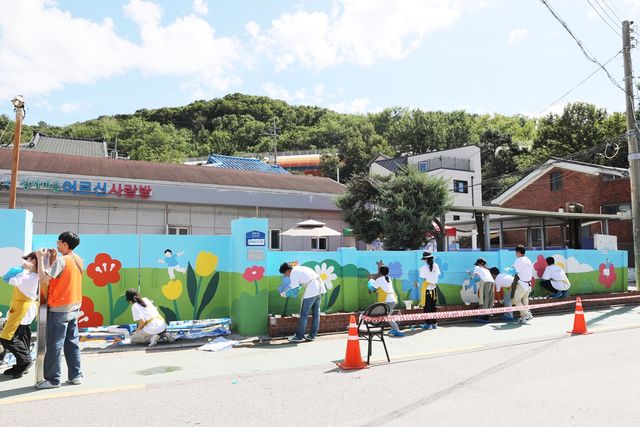 지난 18일 서울 강서구 상사마을 경로당 벽화 봉사에 참여한 오스템임플란트 직원들이 채색 작업을 진행하고 있다. [사진=오스템임플란트]