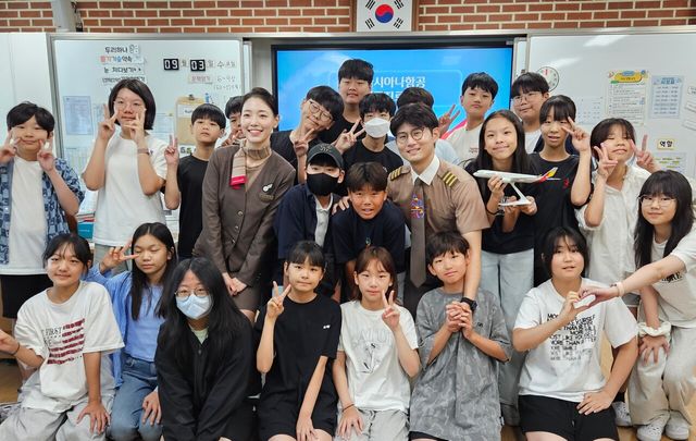 3일 서울공진초등학교에서 열린 항공진로 직업특강에서 (왼쪽부터)이민정 부사무장, 이동준 부기장이 학생들과 기념촬영을 하고 있다. [사진=아시아나항공]
