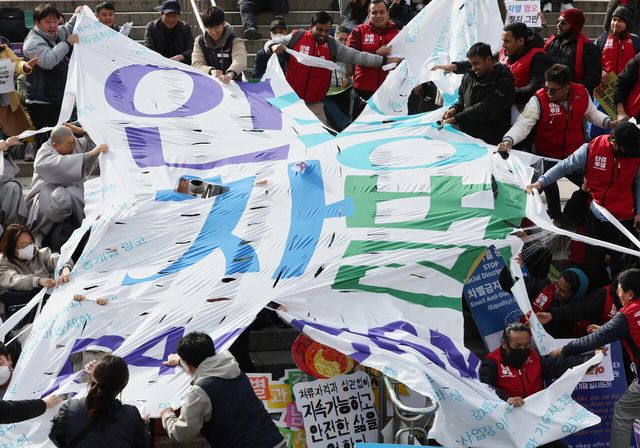 이주인권단체연합 회원들이 2024년 3월 서울 중구 서울역 광장에서 열린 2024 세계 인종차별 철폐의 날 기념대회에서 인종 차별 현수막을 찢고 있다. [사진제공=뉴시스]