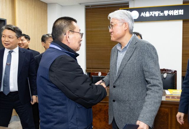 지난 14일 밤 서울 영등포구 서울지방노동위원회에서 진행된 특별조정위원회 2차 사후 조정회의에서 교섭을 타결한 뒤 버스노조 박점곤 위원장과 서울시버스운송사업조합 김정환 이사장이 악수하고 있다. [사진제공=뉴시스]
