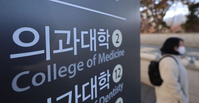 지난 6일 서울 시내 의과대학 간판 곁으로 한 시민이 지나가고 있다. [사진제공=뉴시스]