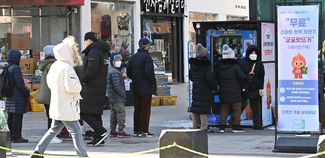 지난 21일 경기 군포시 산본동 로데오거리에 설치된 무료 스마트 핫팩 자판기에서 시민들이 줄을 서고 있다. [사진제공=뉴시스]