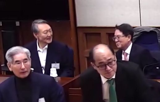 윤석열(왼쪽 위) 전 대통령이 19일 서울 서초구 서울중앙지방법원에서 열린 내란 우두머리 혐의 사건 1심 선고기일에서 변호인과 대화하며 잠시 미소짓고 있다. 법원은 내란 우두머리 혐의로 기소된 윤 전 대통령에게 무기징역을 선고했다. [사진제공=서울중앙지법]