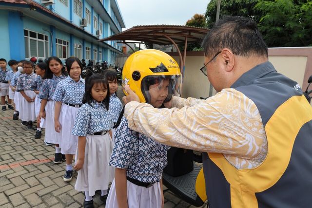 지난 3일 인도네시아 자카르타 단비초등학교에서 열린 ‘KB Green Ride’ 전달식에서 KB손해보험 곽종득 인도네시아 법인장(맨 오른쪽)이 학생들에게 안전모를 씌워주고 있다. [사진=KB손해보험]