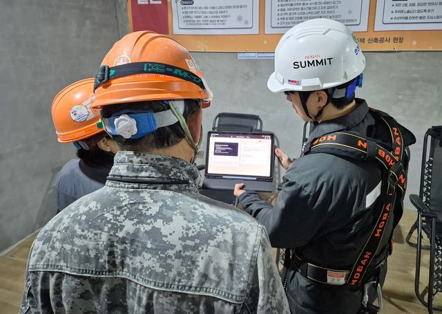 호반건설 직원이 건설 현장에서 AI 동시번역 시스템을 활용해 근로자들과 대화하고 있다. [사진=호반그룹]
