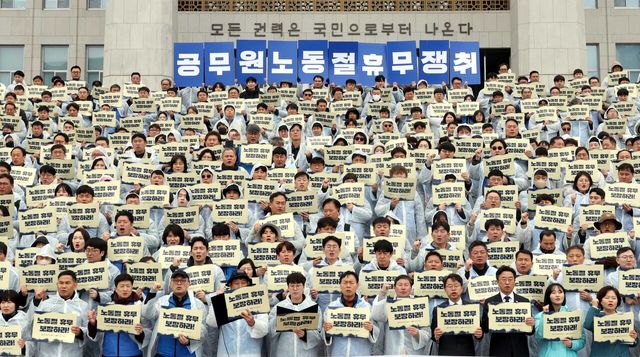 18일 서울 여의도 국회 본청 계단에서 진행된 ‘공무원 5.1 노동절 휴무 쟁취 기자회견’에서 전국공무원노동조합, 대한민국공무원노동조합총연맹 등 참가자들이 손피켓을 들고 있다. [사진제공=뉴시스]