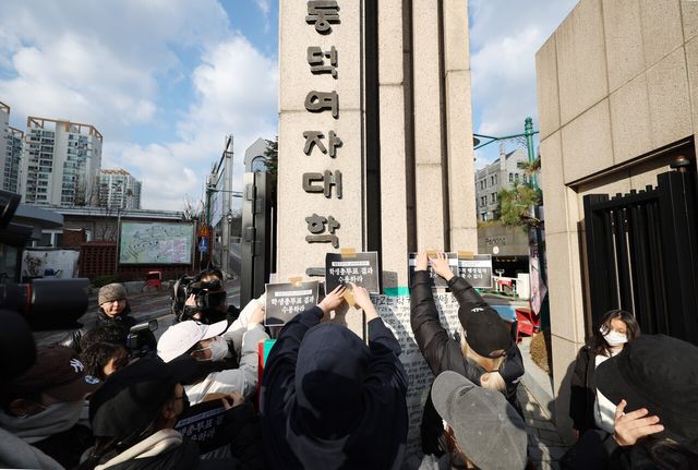 동덕여대 제58대 총학생회 비상대책위원회 등 학생들이 지난해 12월 9일 서울 성북구 동덕여자대학교 정문 앞에서 ‘공학 전환에 대한 8000 동덕인 총투표 결과 전달 기자회견’을 끝낸 뒤 투표 결과 수용을 촉구하는 손팻말을 정문에 부착하고 있다. [사진제공=뉴시스]